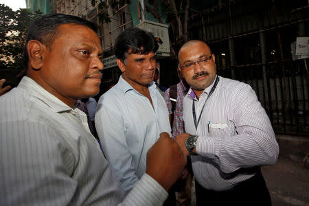 FILE PHOTO: India's Central Bureau of Investigation (CBI) officials escort Gokulnath Shetty, one of the Punjab National Bank employees accused of steering fraudulent loans to companies linked to billionaire jeweller Nirav Modi, outside a court in Mumbai, India, March 3, 2018. REUTERS/Francis Mascarenhas/File photo