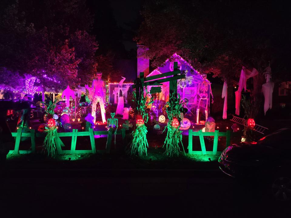 Purple and green lights illuminate the front lawn of 1233 E. Linwood St. in Springfield. Large skeletons, pumpkins, ghosts and spiderwebs decorate the front porch and lawn.