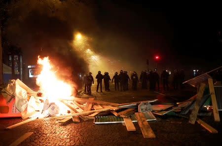 Police officers are seen behind a burning barricade during a "Yellow vest" protests against higher fuel prices, on the Champs-Elysees in Paris, France, November 24, 2018. REUTERS/Benoit Tessier