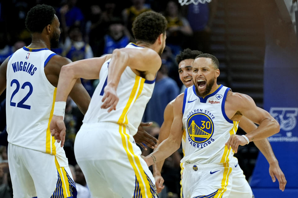 Golden State Warriors guard Stephen Curry (30) celebrates with forward Andrew Wiggins (22), guard Klay Thompson, and forward Trayce Jackson-Davis, rear, after making a shot against the Orlando Magic in the closing seconds of an NBA basketball game Wednesday, March 27, 2024, in Orlando, Fla. (AP Photo/John Raoux)