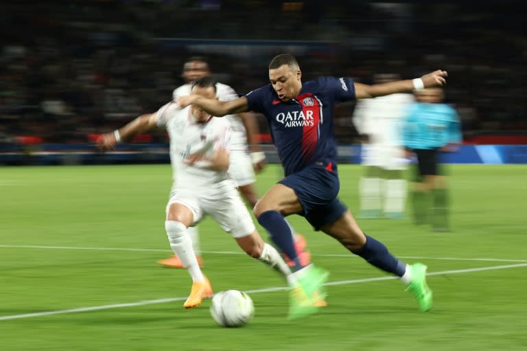 El delantero del PSG Kylian Mbappé (d) conduce el balón ante la presión de un rival del Clermont en un partido de la liga francesa en el Parque de los Príncipes el 6 de abril de 2024. (FRANCK FIFE)