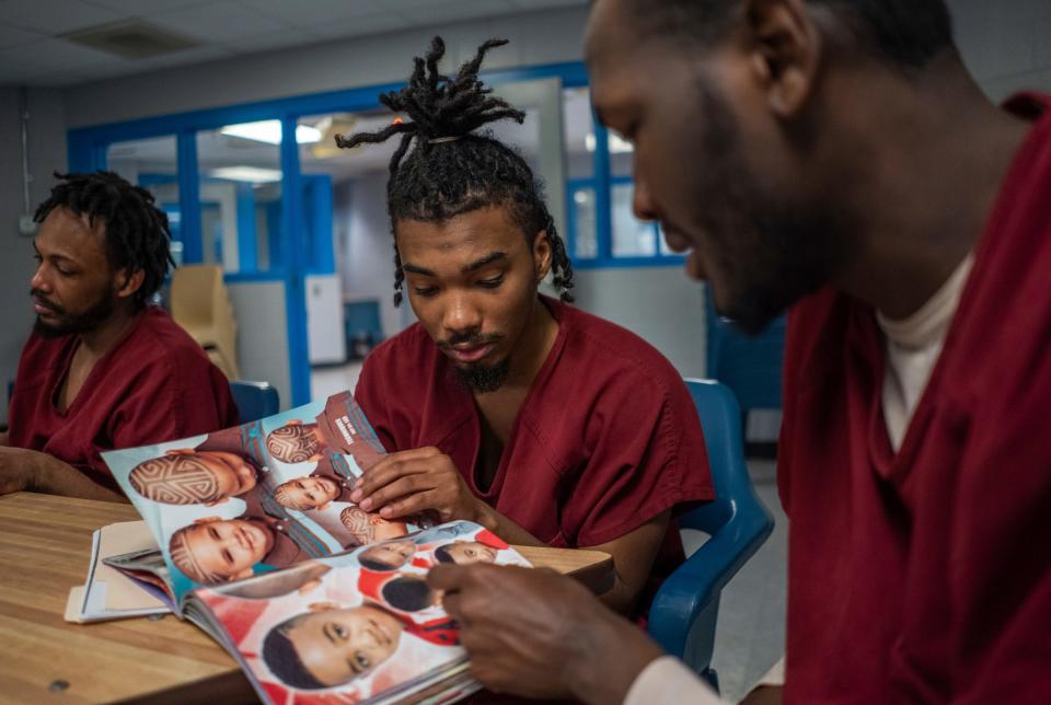 Stanlee Fells, center, and Calvin Robinson, right, look through a book of hairstyles for inspiration during a one-hour barber course for a small group of incarcerated men as part of the I.G.N.I.T.E. (Inmate Growth Naturally and Intentionally Through Education) program held in an activities room of the Genesee County Jail in Flint on Wednesday, Jan. 3, 2024.