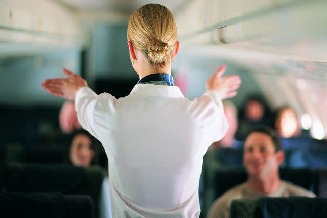 <p>Getty</p> Flight attendant instructing passengers on an airplane