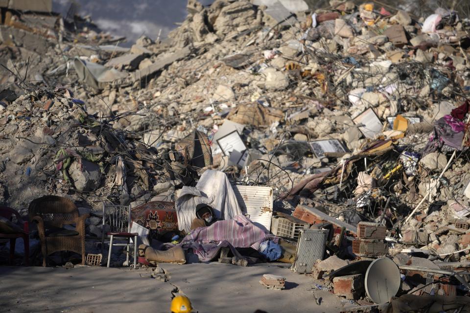 A man sleeps in front of a destroyed building in Kahramanmaras, southeastern Turkey, Monday, Feb. 13, 2023. Ever since the powerful 7.8 earthquake that has become Turkey's deadliest disaster in modern history, survivors have been gathering outside destroyed buildings, refusing to leave. (AP Photo/Khalil Hamra)