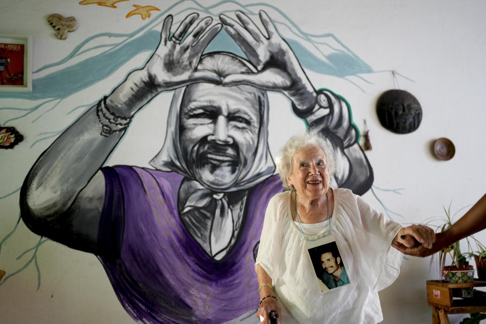 Nora Cortinas, de 94 años, posa para un retrato con una fotografía de su hijo desaparecido Gustavo en su casa, decorada con un mural suyo, en las afueras de Buenos Aires, Argentina, el lunes 29 de enero de 2024. Cortinas se convirtió en una de muchas madres cuyos hijos fueron secuestrados por el Estado, dando origen a lo que hoy es la organización de derechos humanos Madres de Plaza de Mayo. (AP Foto/Natacha Pisarenko)