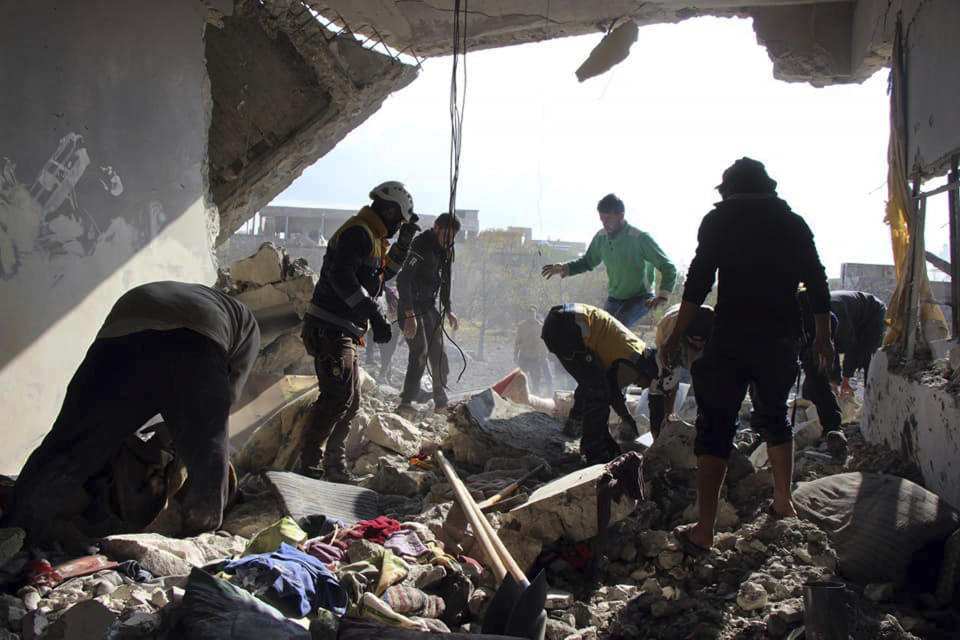 This photo released by the opposition Syrian Civil Defense rescue group, also known as White Helmets, which has been authenticated based on its contents and other AP reporting, shows Civil Defense workers and people searching for victims under the rubble of a destroyed building that was hit by airstrikes in the village of Ibdeita, in Idlib province, Syria, Saturday, Dec. 7, 2019. Airstrikes on areas in the last major rebel stronghold in northwest Syria on Saturday killed at least 18 people, including women and children, and wounded others as a three-month truce crumbles, opposition activists said. (Syrian Civil Defense White Helmets via AP)