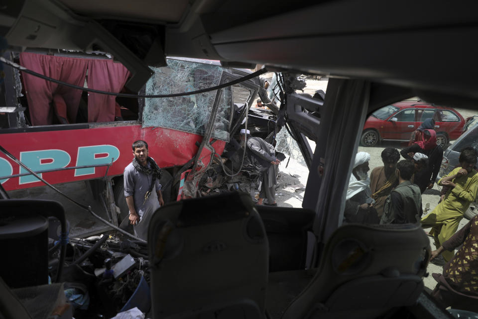 Afghan men stand near damaged buses after a deadly accident on the Kabul-Kandahar highway, on the outskirts of Kabul, Afghanistan, Tuesday, April 27, 2021. Two buses crashed head-on killing several people and injuring more than 70, an Afghan official said Tuesday. (AP Photo/Rahmat Gul)