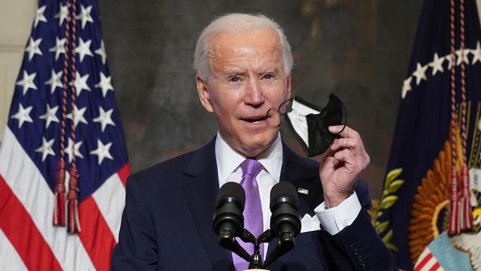 President Biden holds up a face mask as he speaks about the fight to contain the coronavirus pandemic, Jan. 26. (Kevin Lamarque/Reuters)