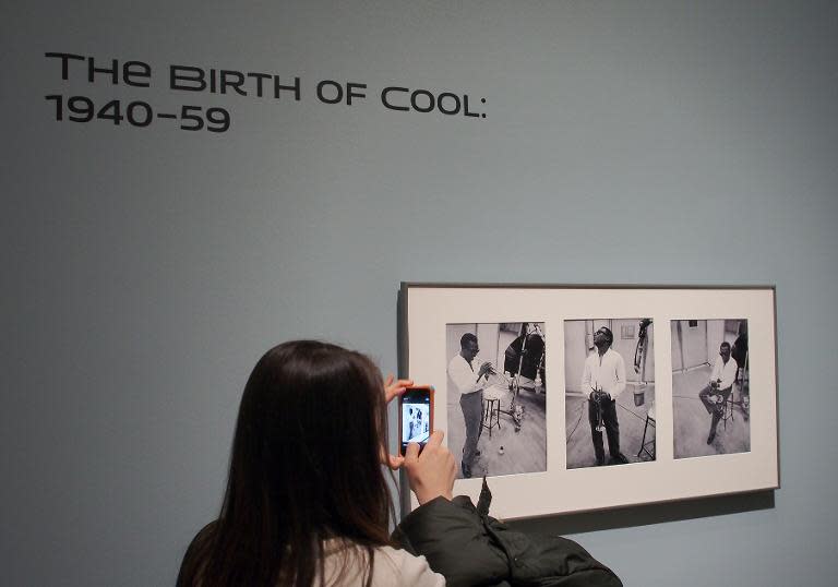 A visitor takes a photo of a triptych of jazz legend Miles Davis by Arma Avakian at a February 5, 2014 press preview of the "American Cool" exhibition at the National Portrait Gallery in Washington, DC