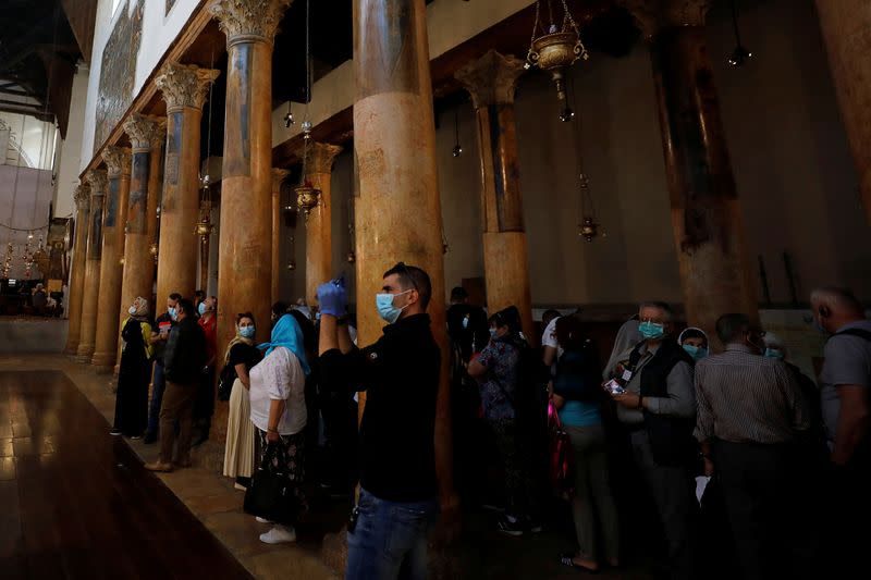 A visitor wearing a mask as a preventive measure against the coronavirus takes pictures in the Church of the Nativity in Bethlehem in the Israeli-occupied West Bank