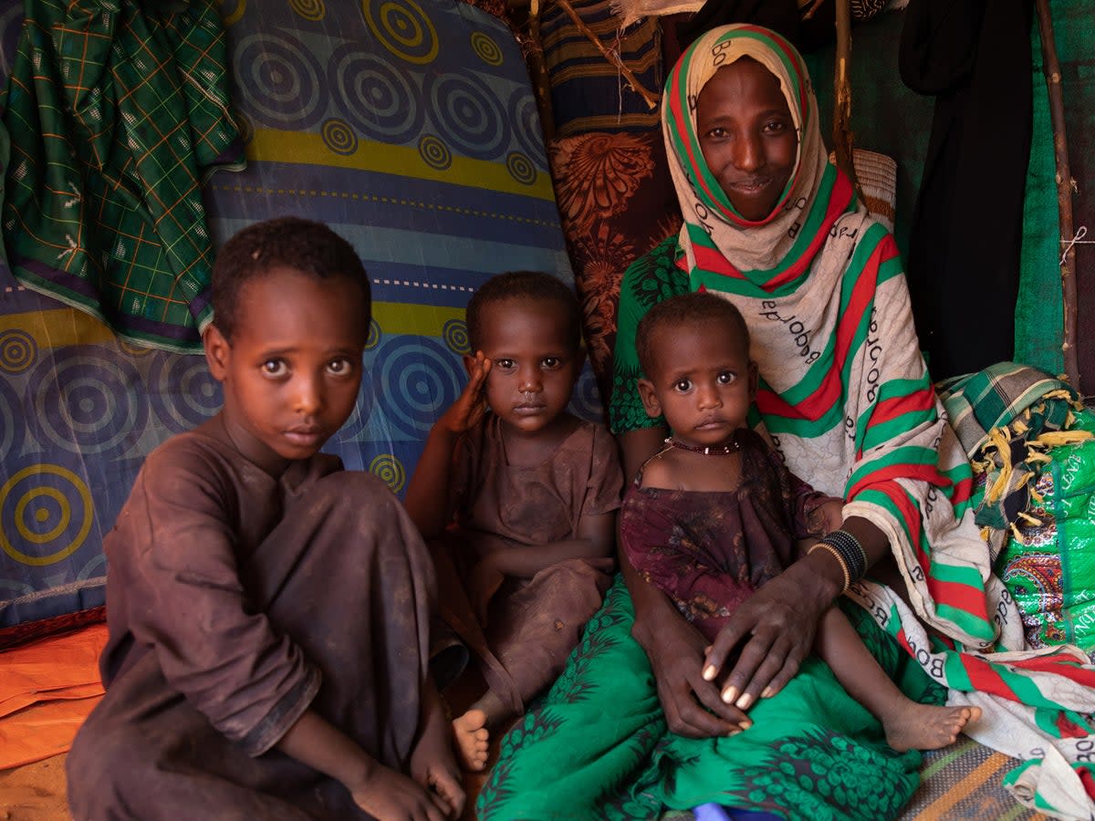 Mido poses with three of her children inside the small shelter they now call home (WFP/Samantha Reinders)