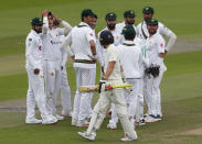 Pakistan players celebrate as they watch England's Rory Burns, center with bat, walk off the field after his dismissal during the fourth day of the first cricket Test match between England and Pakistan at Old Trafford in Manchester, England, Saturday, Aug. 8, 2020. (Lee Smith/Pool via AP)