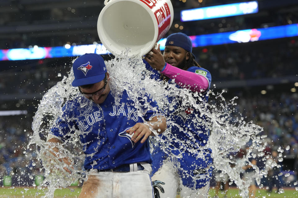 Toronto Blue Jays first baseman Vladimir Guerrero Jr., right, pours ice water over teammate Davis Schneider, left, after they defeated the Cleveland Guardians in a baseball game in Toronto, Saturday, Aug. 26, 2023. (Frank Gunn/The Canadian Press via AP)
