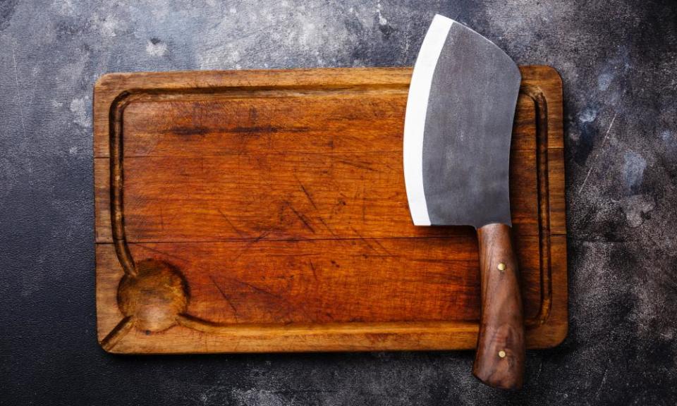 Meat cleaver and empty chopping board against dark grey background