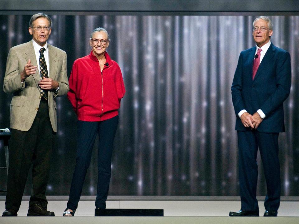 Jim Walton, Alice Walton, and Robson Walton stand on stage during Walmart event