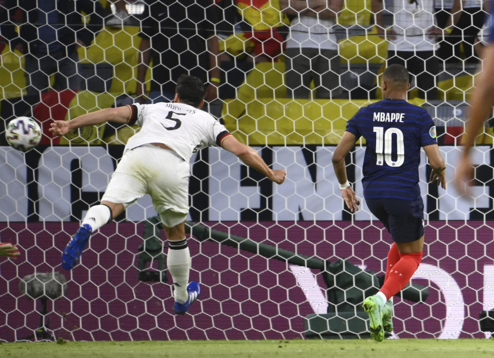 France's Kylian Mbappe, right, looks as Germany's Mats Hummels scores an own goal during the Euro 2020 soccer championship group F match between Germany and France at the Allianz Arena stadium in Munich, Tuesday, June 15, 2021. (Franck Fife/Pool via AP)