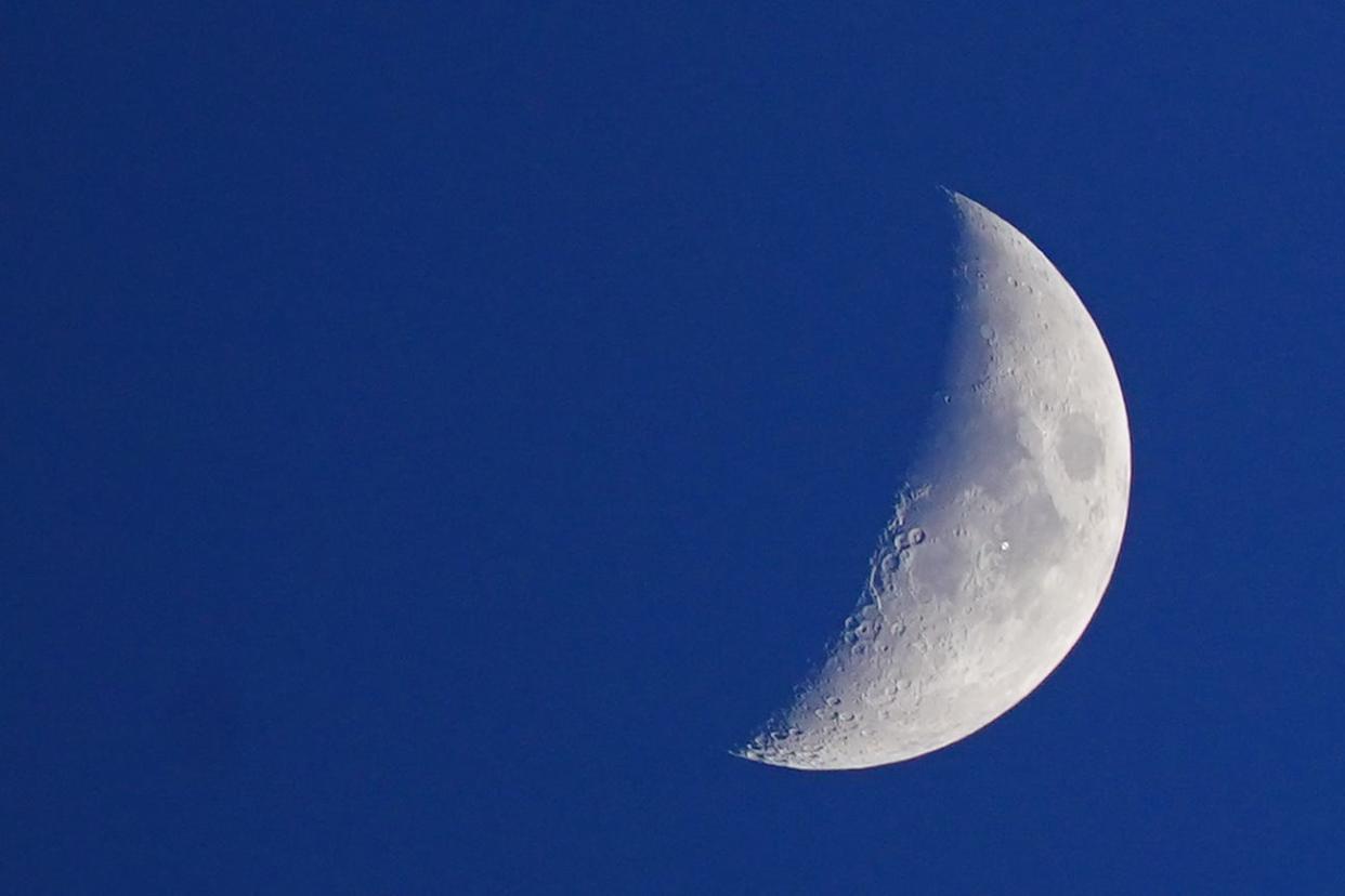 The International Space Station looking like a white dot as it passes the Moon as seen from Liverpool.