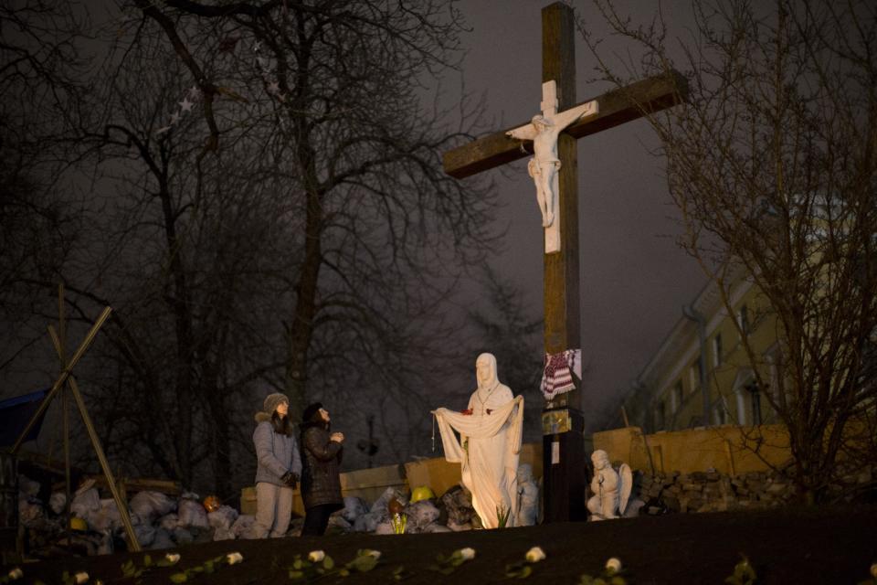 Two woman pray at a memorial for the people killed in clashes with the police at Kiev's Independence Square, the epicenter of the country's current unrest, Ukraine, Tuesday, Feb. 25, 2014. Parliament speaker says that a new government should be in place by Thursday, a delay reflecting intense ongoing consultations. Oleksandr Turchinov has previously said the new government could be formed on Tuesday. Turchinov was named Ukraine's interim leader after President Viktor Yanukovych fled the capital after signing a peace deal with opposition leaders to end violent clashes between police and protesters and Kiev. (AP Photo/Emilio Morenatti)