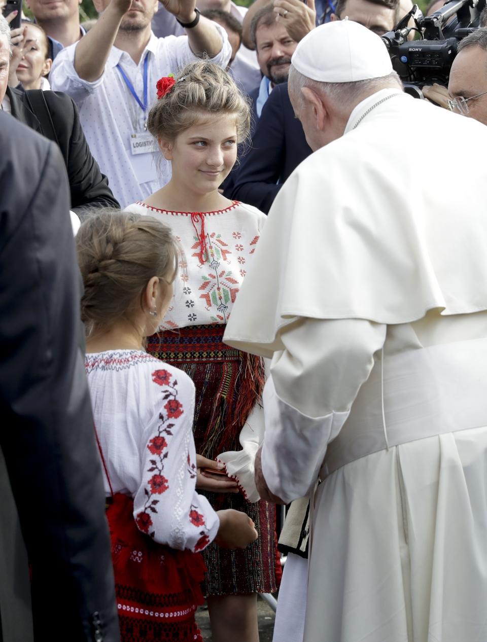 Pope Francis greets two girls as he arrives for a meeting with young people and families, in Iasi, Romania, Saturday, June 1, 2019. Francis began a three-day pilgrimage to Romania on Friday that in many ways is completing the 1999 trip by St. John Paul II that marked the first-ever papal visit to a majority Orthodox country. (AP Photo/Andrew Medichini)