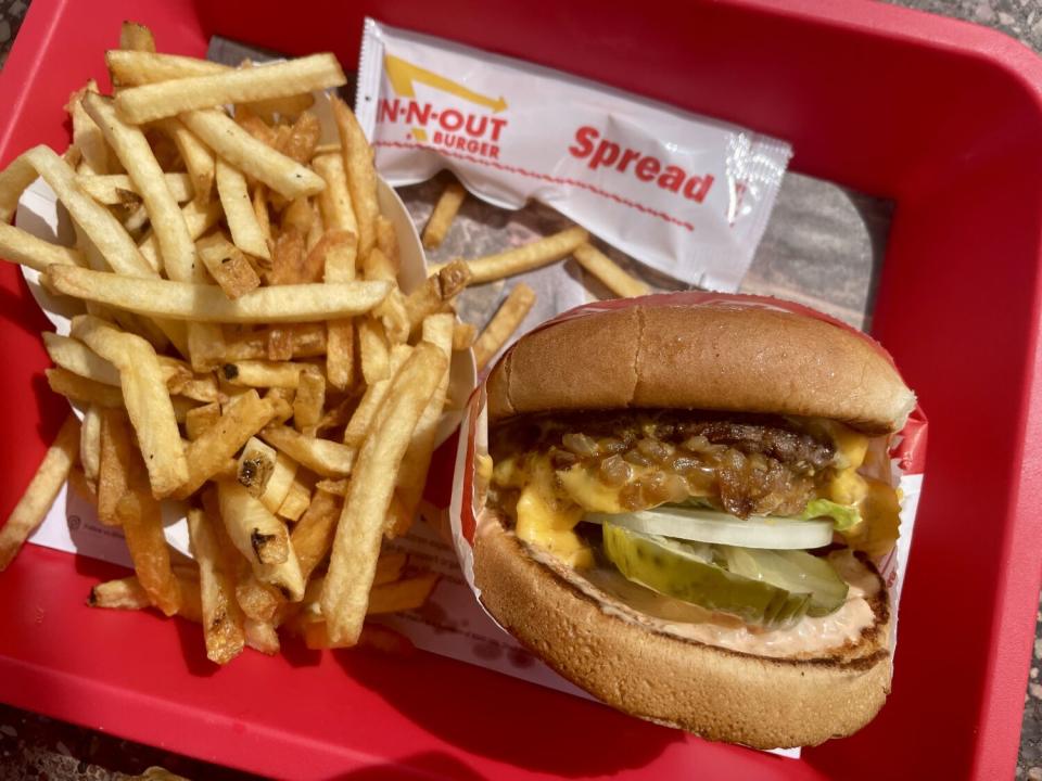 A red tray holds a hamburger and french fries