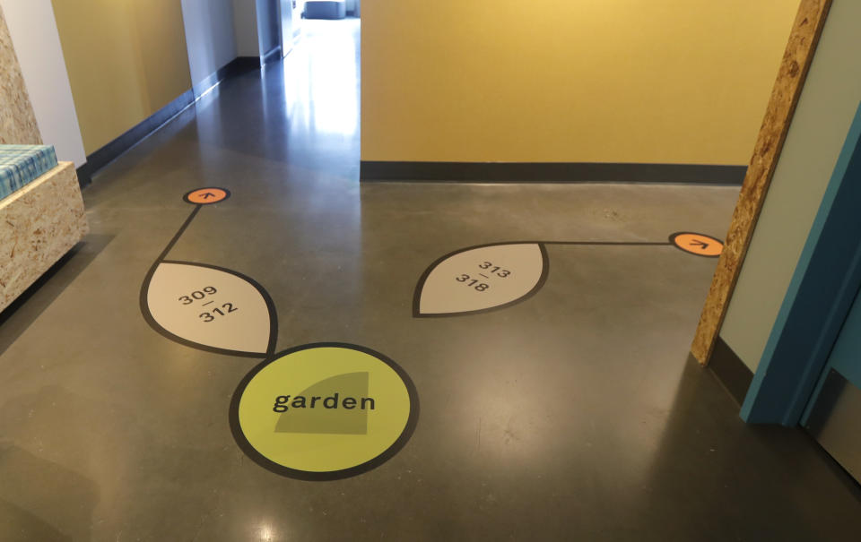 Signs on the floor point the way to rooms and a garden at Mary's Place, a family homeless shelter located inside an Amazon corporate building on the tech giant's Seattle campus, Wednesday, June 17, 2020. The shelter marks a major civic contribution bestowed by Amazon to the hometown it has rapidly transformed. (AP Photo/Ted S. Warren)