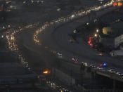 Smoke rises from a small fire as motorists exit through a ramp off Interstate 10, where a section of the freeway is closed due to a recent fire in Los Angeles, Tuesday, Nov. 14, 2023. It will take at least three weeks to repair the freeway damaged in an unrelated arson fire, the California governor said Tuesday, leaving the city already accustomed to soul-crushing traffic without part of a vital artery that serves hundreds of thousands of people daily. (AP Photo/Jae C. Hong)