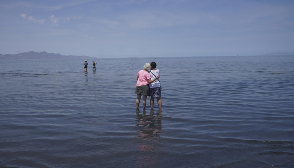 Visitors stand in the shallow waters of the Great Salt Lake on June 17, 2021, near Salt Lake City. The silvery blue waters of the lake sprawl across the Utah desert, having covered an area nearly the size of Delaware for much of history. For years, though, the largest natural lake west of the Mississippi River has been shrinking. And a drought gripping the American West could make this year the worst yet. (AP Photo/Rick Bowmer)