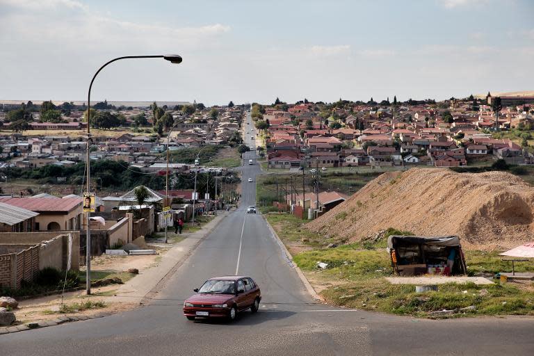 A car approaches an intersection in Soweto on April 15, 2014, visible in the background is a recently built urban development