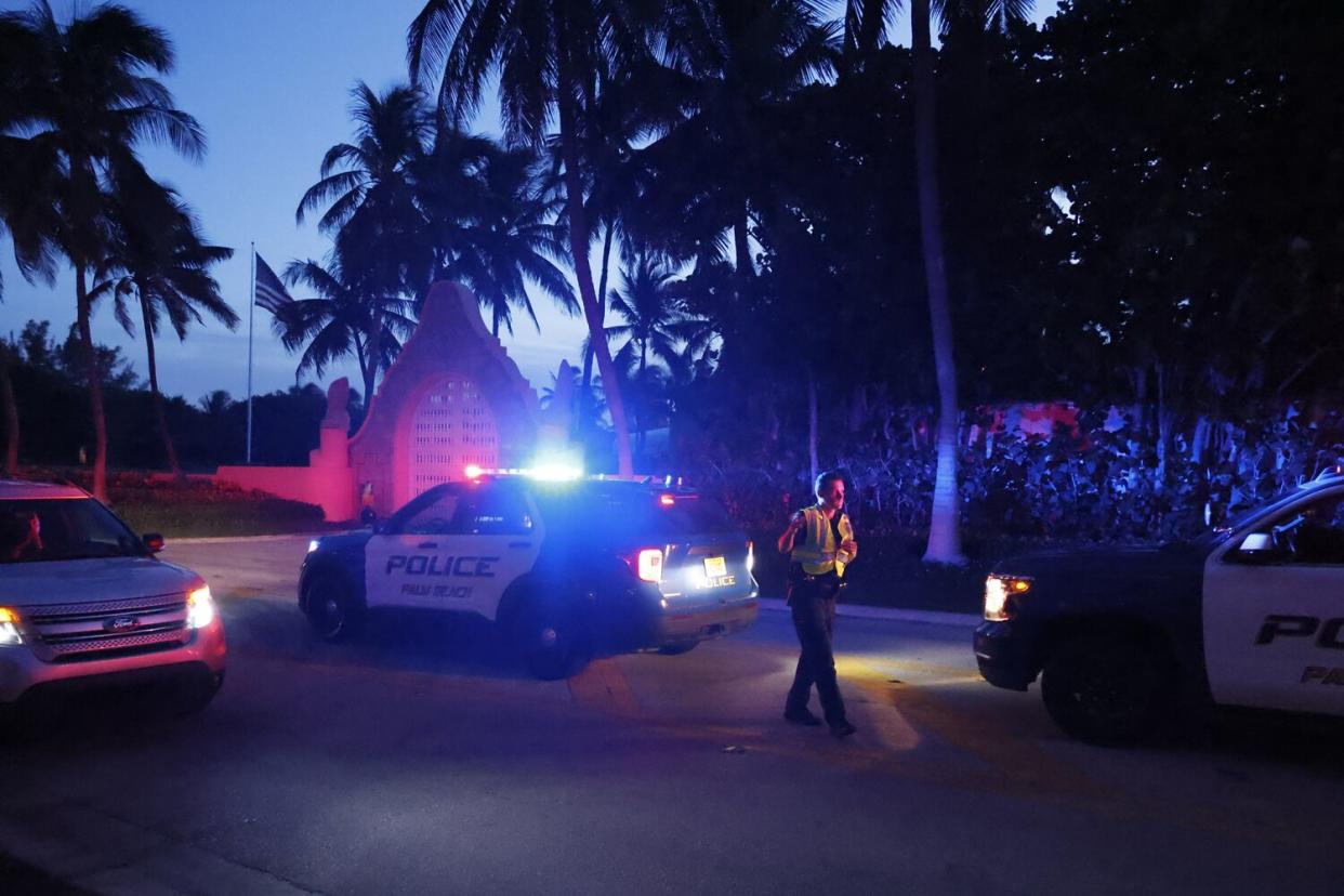 Police directing traffic in the dark next to a property with palm trees