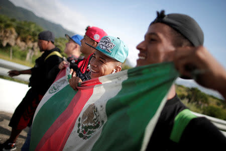 Migrants traveling with a caravan of thousands from Central America en route to the United States, hold Mexico's national flag during walk along the highway to Juchitan from Santiago Niltepec, Mexico, October 30, 2018. REUTERS/Ueslei Marcelino