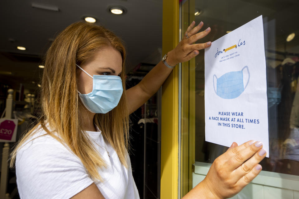 Joanne Millar store manger of Joules in Belfast places a sign in the shop window advising customers that face masks must be worn at all times as face coverings are now compulsory for shoppers in Northern Ireland.