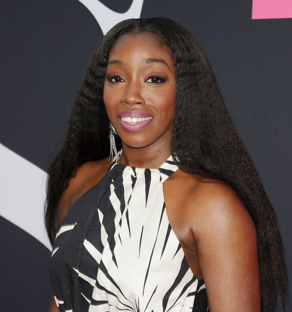 Estelle poses on the red carpet in a sleeveless, printed dress with straight, long hair