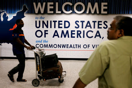 FILE PHOTO: An international passenger (L) arrives at Dulles International Airport as a man (R) waits for loved ones to arrive in Dulles, Virginia, U.S. September 24, 2017. REUTERS/James Lawler Duggan/File Photo