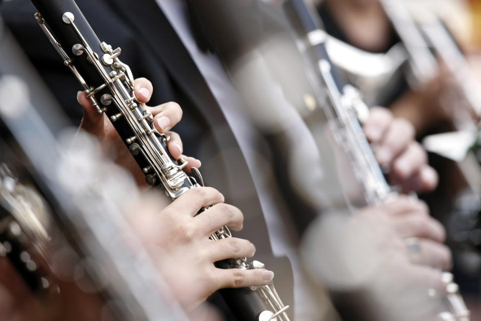 Close-up of musicians playing clarinets, focused on their hands and instruments, dressed in formal attire