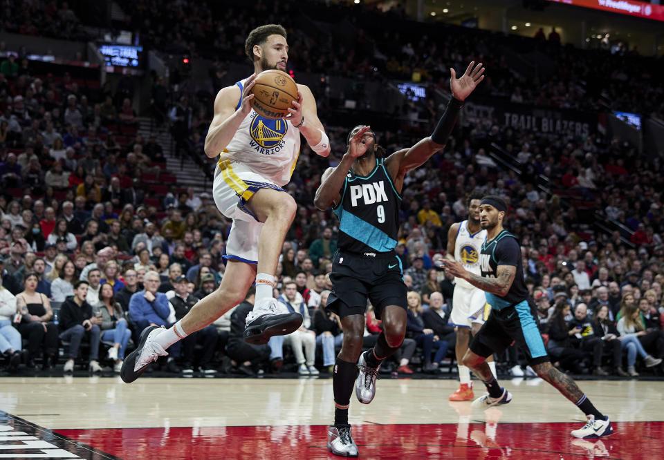 Golden State Warriors guard Klay Thompson, left, looks to pass the ball away from Portland Trail Blazers forward Jerami Grant during the first half of an NBA basketball game in Portland, Ore., Wednesday, Feb. 8, 2023. (AP Photo/Craig Mitchelldyer)