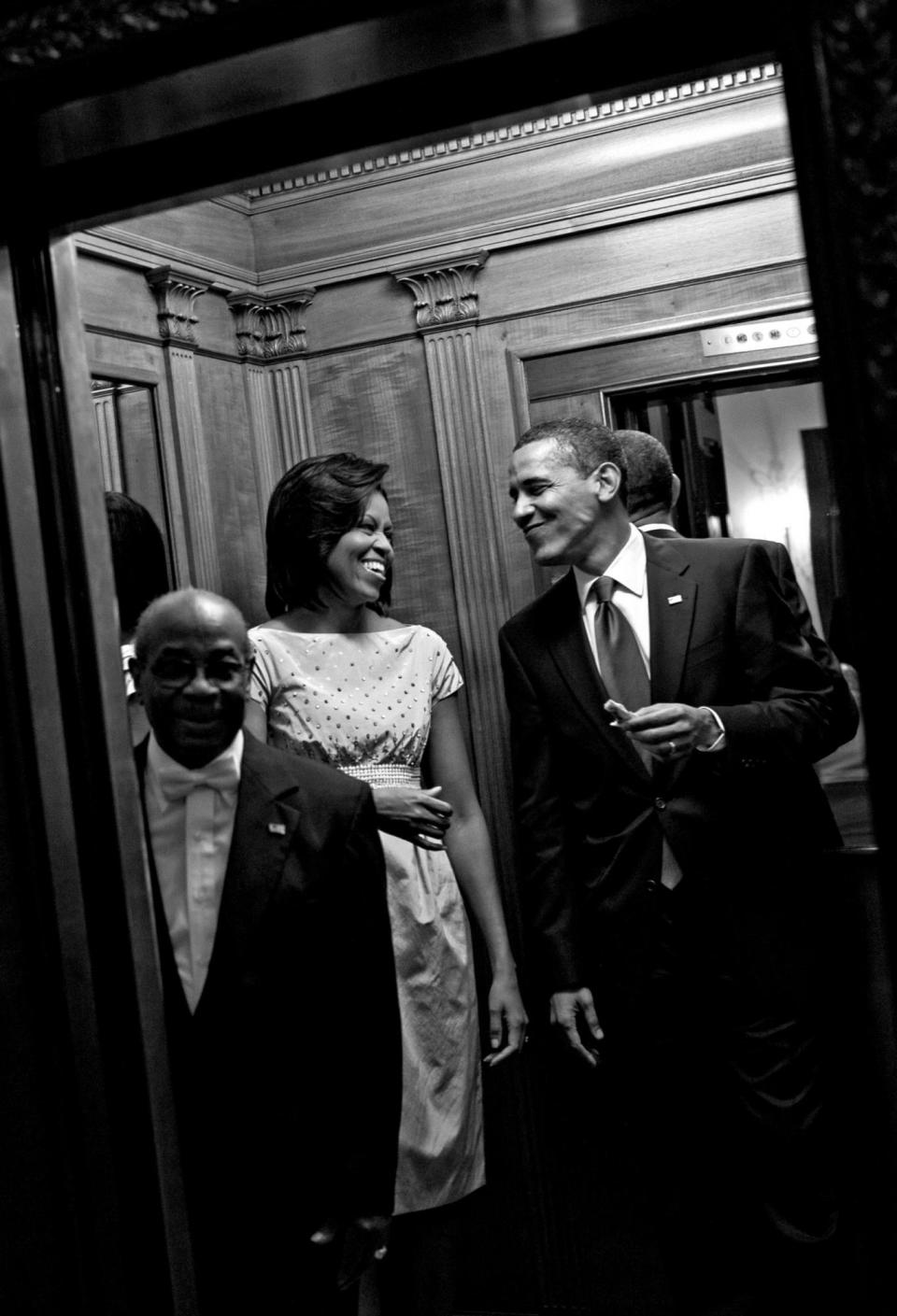 Michelle Obama and her husband laughing as he eats a snack in the White House lift after the celebration of Cinco de Mayo in 2009. (Official White House Photo by Samantha Appleton)