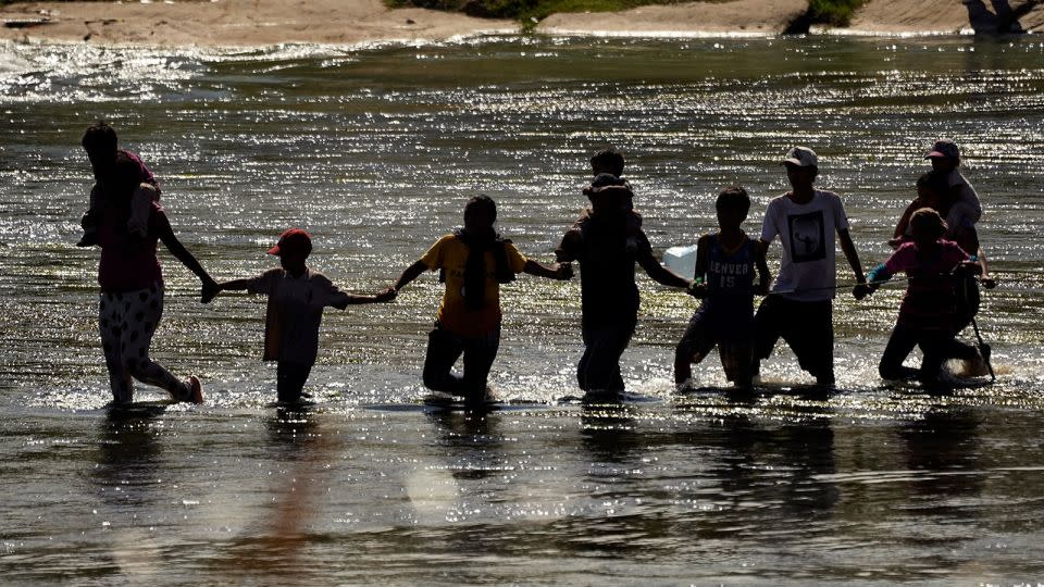 Migrants join hands as they cross the Rio Grande from Mexico into the US, on Thursday, Sept. 21, 2023, in Eagle Pass, Texas. - Eric Gay/AP