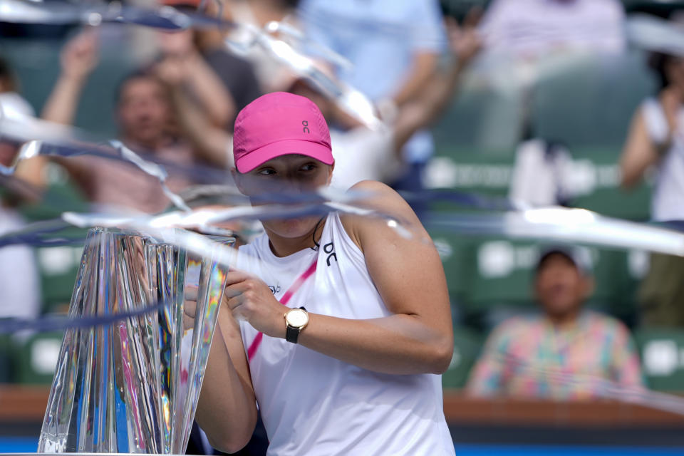 Iga Swiatek, of Poland, reacts as she stands next to the trophy after defeating Maria Sakkari, of Greece, in the final match at the BNP Paribas Open tennis tournament, Sunday, March 17, 2024, in Indian Wells, Calif. (AP Photo/Ryan Sun)