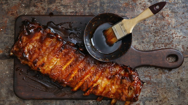Barbecued ribs and sauce brush on a cutting board