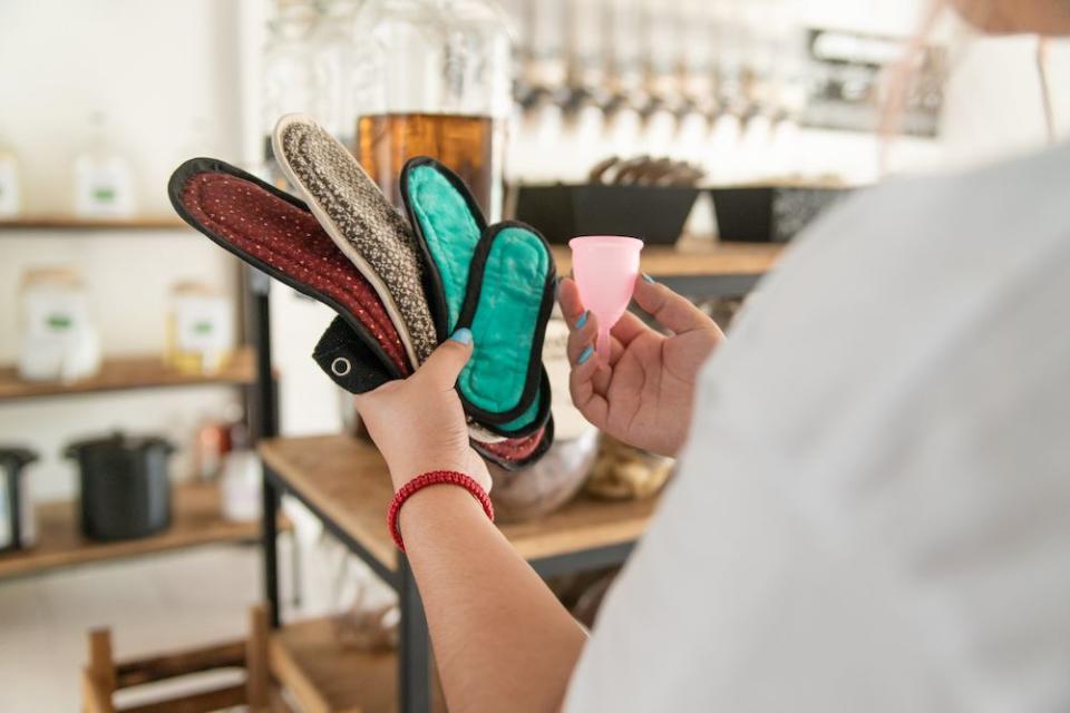 woman comparing different reusable period products, pads and menstrual cups