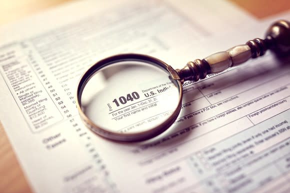 Magnifying glass on top of a 1040 tax return.