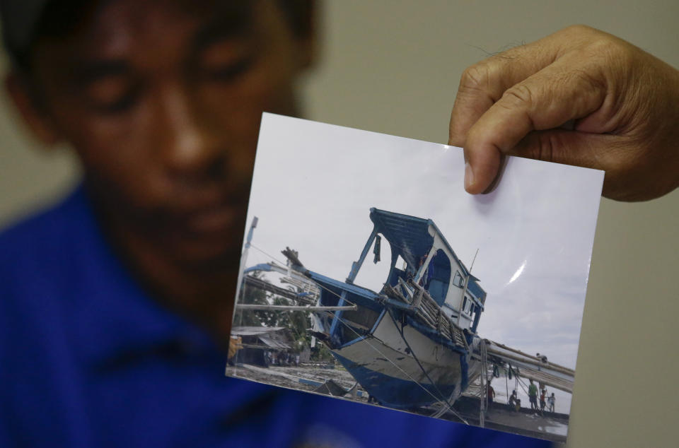 FILE - In this June 17, 2019, file photo, a photo of the damaged Filipino fishing vessel F/B Gimver 1 is shown by one of it's crew Richard Blaza, left, during a press conference by Department of Agriculture Secretary Emmanuel Pinol in metropolitan Manila, Philippines. The Philippines' top diplomat says he has filed a diplomatic protest after an anchored fishing boat was hit by a suspected Chinese vessel which then abandoned the 22 Filipino fishermen as the boat sank in the disputed South China Sea. (AP Photo/Aaron Favila, File)