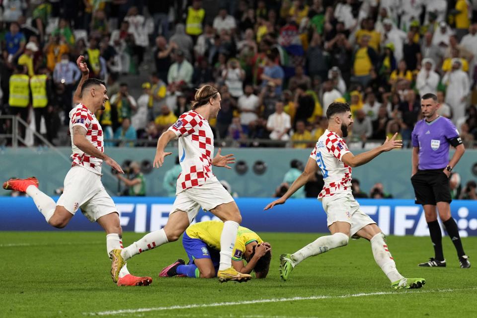 Brazil's Marquinhos lies on the ground as Croatia's player celebrate after the penalty shootout at the World Cup quarterfinal soccer match between Croatia and Brazil, at the Education City Stadium in Al Rayyan, Qatar, Friday, Dec. 9, 2022. (AP Photo/Martin Meissner)
