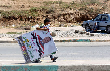 An Iraqi boy carries election posters in Mosul, Iraq May 13, 2018. REUTERS/Khalid al-Mousily