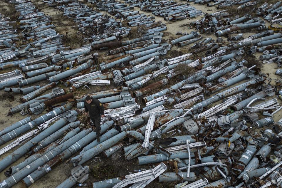 A war prosecutor observes collected parts of Russian rockets which were used to attack the city of Kharkiv, in Kharkiv, Ukraine, Thursday, Dec. 22, 2022. (AP Photo/Evgeniy Maloletka)