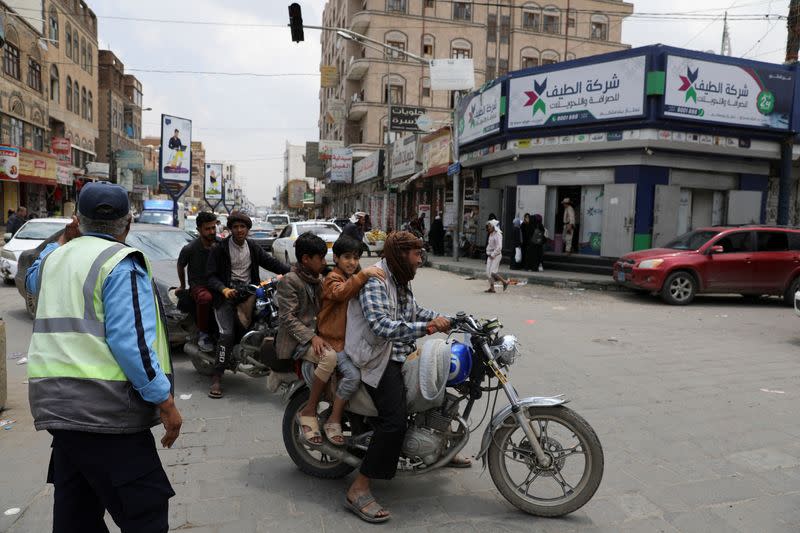 People ride on motorbikes on a street in Sanaa