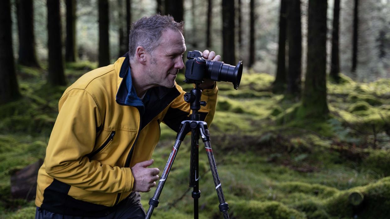  Manfrotto  Befree Advanced Carbon Fibre Travel Tripod, man looking through viewfinder. 