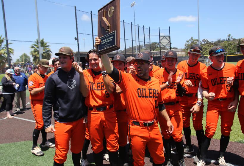 Huntington Beach's head coach Benji Medure holds the CIF Championship plaque as he celebrates with his team winning the CIF State Southern California Regional Division I baseball final against JSerra Catholic High School at JSerra Catholic School in San Juan Capistrano on Saturday, June 4, 2022. (Photo by James Carbone)