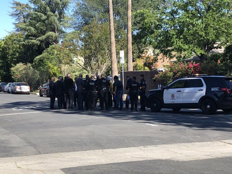 Investigators gather near the scene where an off-duty LAPD officer was shot on Wednesday.