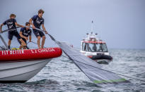Team New Zealand crewmen grab the sail of United States' American Magic's boat, Patriot, after it capsized during its race against Italy's Luna Rossa on the third day of racing of the America's Cup challenger series on Auckland's Waitemate Harbour, New Zealand, Sunday, Jan. 17, 2021. (Michael Craig/NZ Herald via AP)